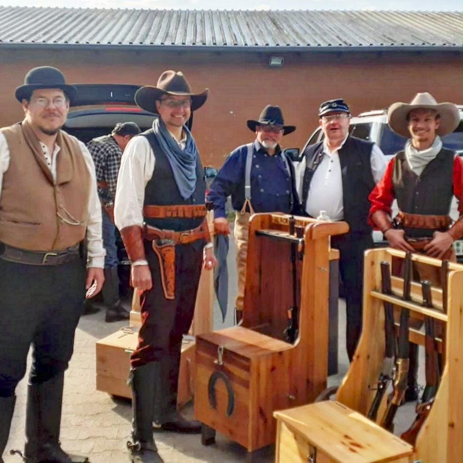 Cowboy-Action-Schützen in Westernkleidung mit hölzernen Waffenständern beim Wettkampf